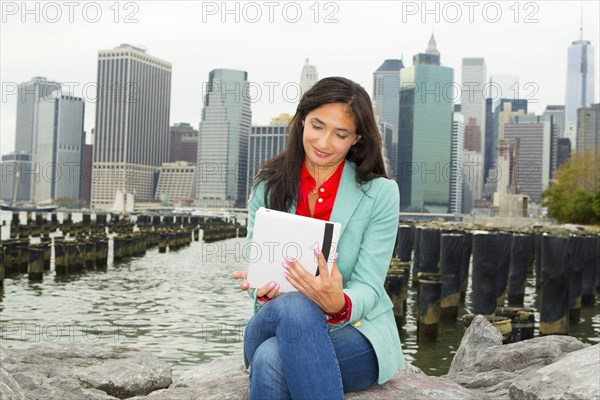 Mixed race woman using digital tablet at waterfront