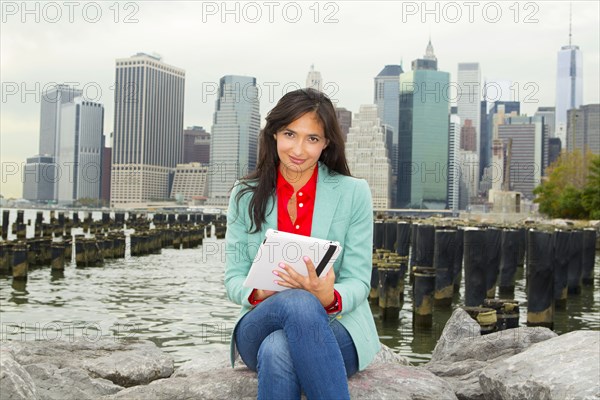 Mixed race woman using digital tablet by urban harbor