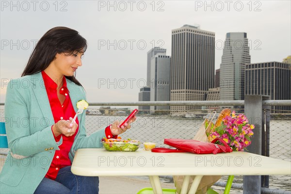 Mixed race woman eating lunch by urban river