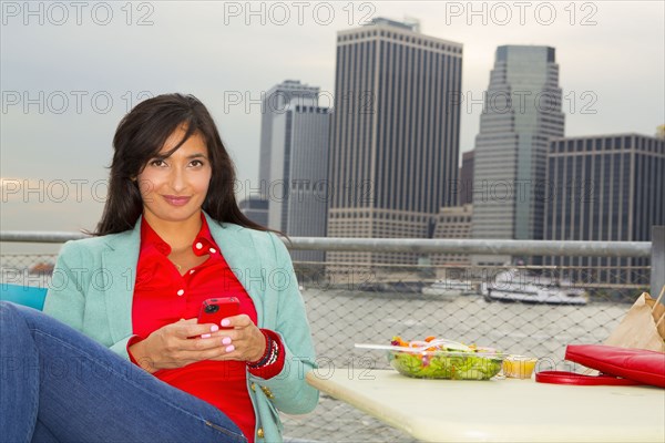 Mixed race woman eating lunch by urban river