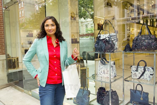 Mixed race woman window shopping at purse shop