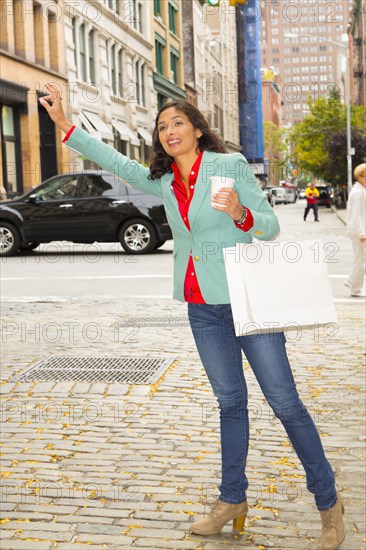 Mixed race woman hailing taxi on city street