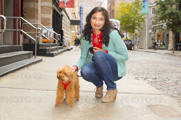 Mixed race woman walking dog on urban sidewalk