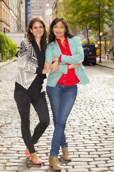 Mixed race women smiling on city street