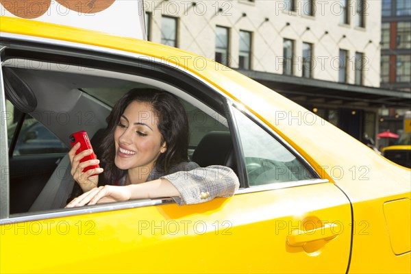 Mixed race woman using cell phone in taxi