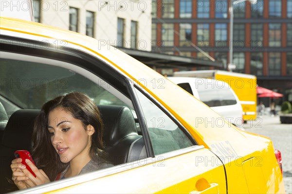 Mixed race woman using cell phone in taxi