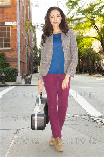 Mixed race woman carrying guitar case