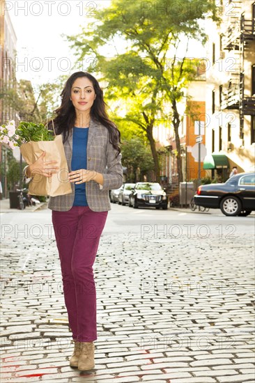 Mixed race woman carrying shopping bag on urban street