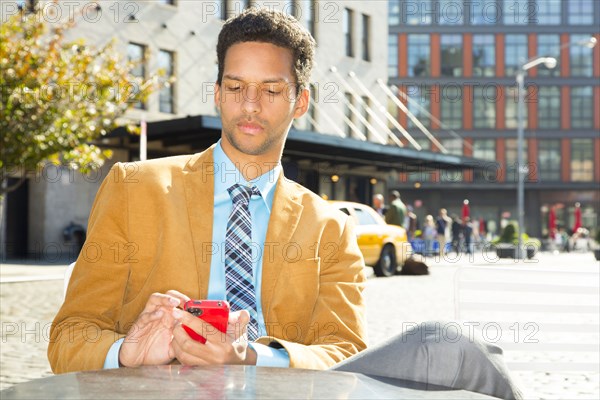 Mixed race businessman using cell phone outdoors