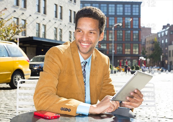 Mixed race businessman using digital tablet outdoors