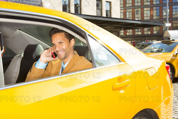 Mixed race businessman on cell phone in taxi