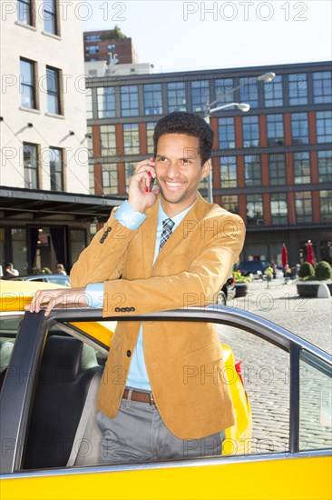 Mixed race businessman using cell phone in taxi