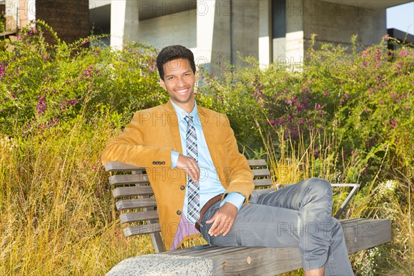 Mixed race businessman smiling on park bench