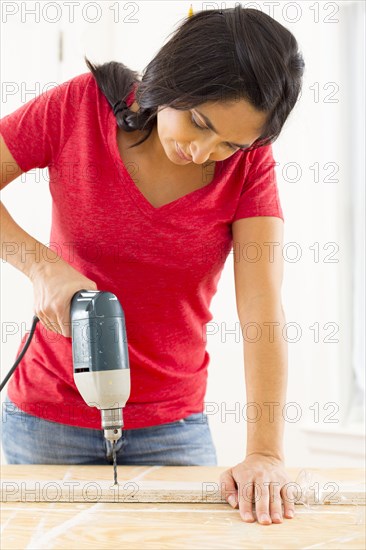 Mixed race woman using power drill