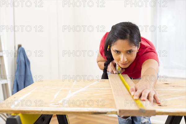 Mixed race woman measuring plank of wood