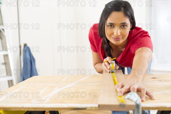 Mixed race woman measuring plank of wood