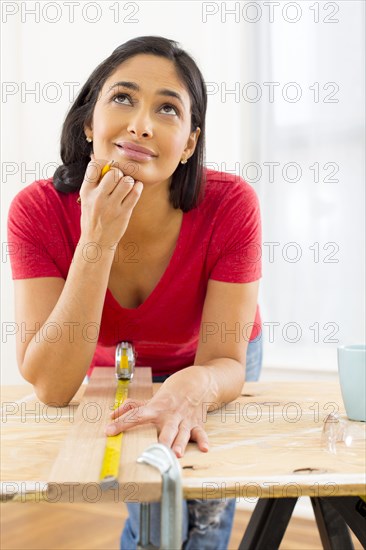 Mixed race woman measuring plank of wood