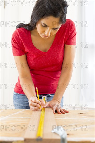 Mixed race woman measuring plank of wood