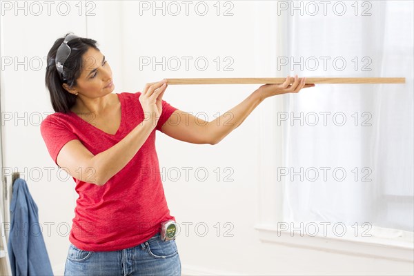 Mixed race woman examining plank of wood