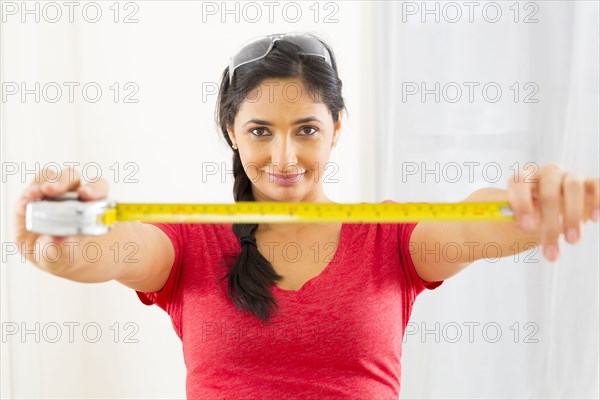 Mixed race woman using measuring tape