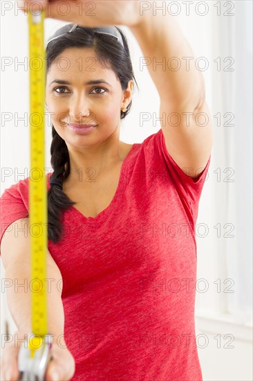 Mixed race woman using measuring tape