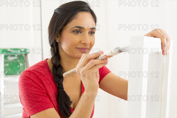 Mixed race woman painting window pane