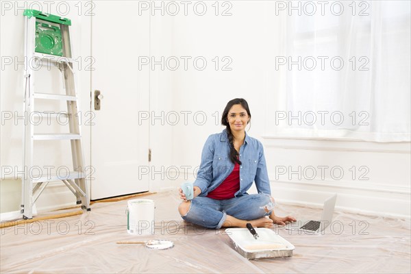 Mixed race woman relaxing while painting room