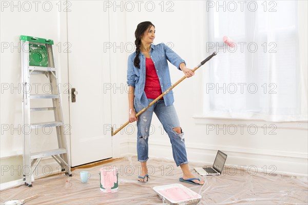 Mixed race woman painting room