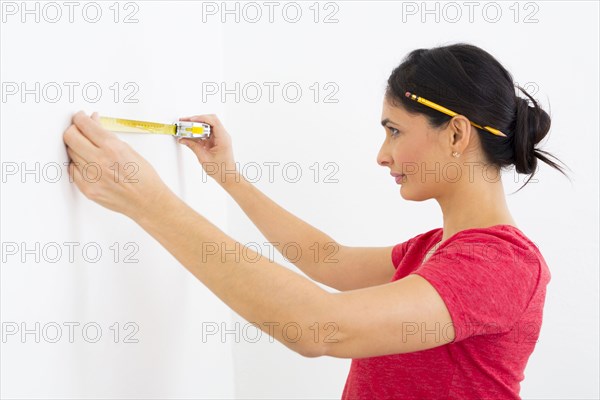 Mixed race woman using measuring tape