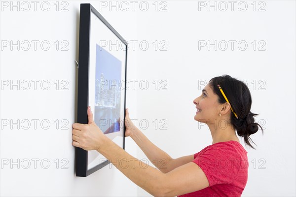 Mixed race woman hanging painting