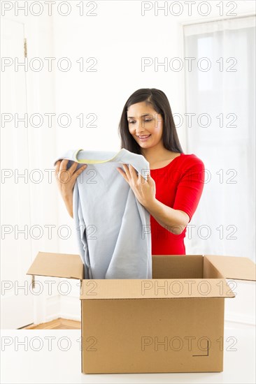 Mixed race woman unpacking cardboard box