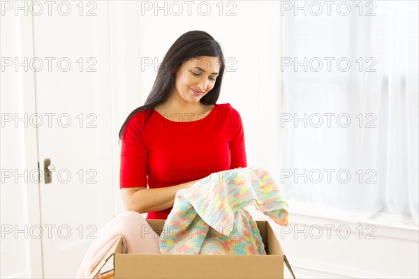 Mixed race woman unpacking cardboard box