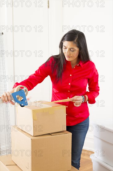 Mixed race woman packing cardboard boxes