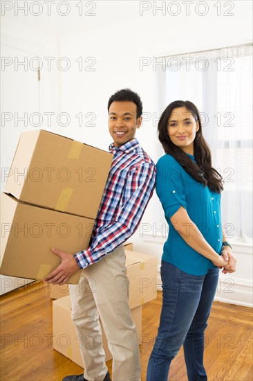 Mixed race couple carrying cardboard boxes in new home