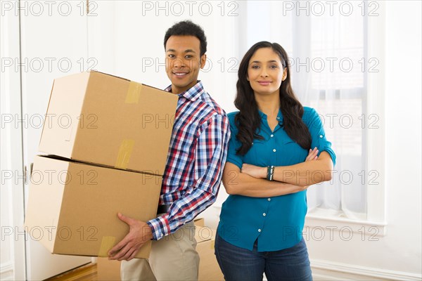 Mixed race couple carrying cardboard boxes in new home