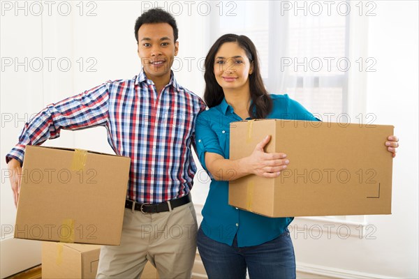 Mixed race couple carrying cardboard boxes in new home