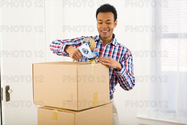 Mixed race man packing cardboard boxes