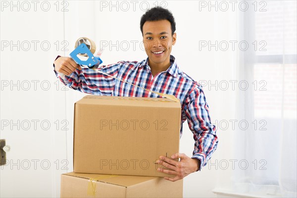 Mixed race man packing cardboard boxes