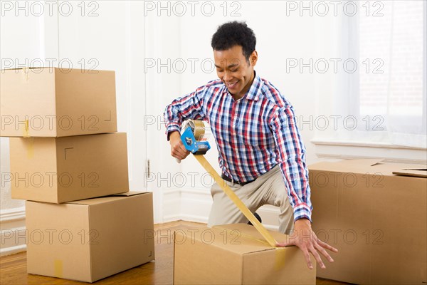 Mixed race man packing cardboard boxes