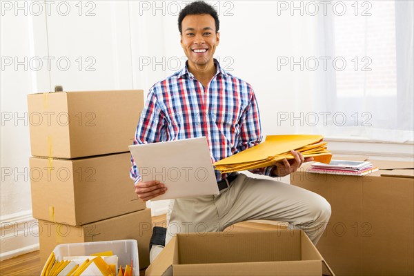 Mixed race man packing cardboard boxes