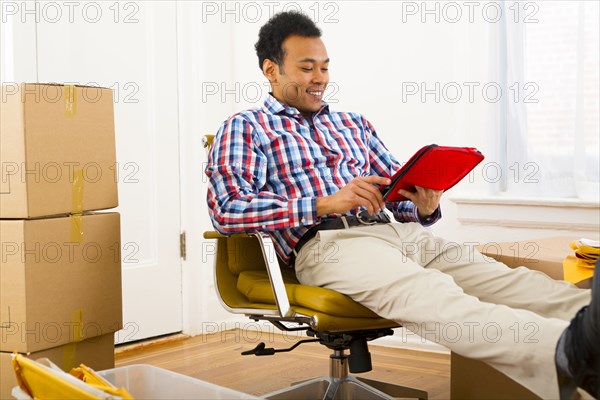 Mixed race man using digital tablet in new home