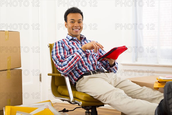 Mixed race man using digital tablet in new home