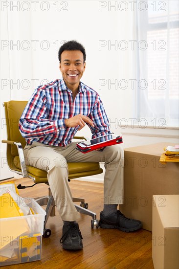 Mixed race man using digital tablet in new home