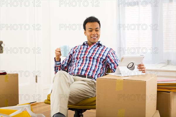 Mixed race man using digital tablet and having cup of coffee