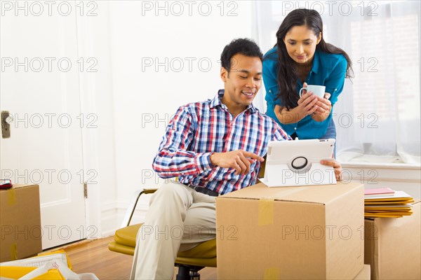 Mixed race couple using digital tablet in new home