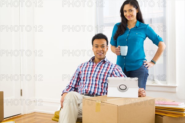 Mixed race couple using digital tablet in new home