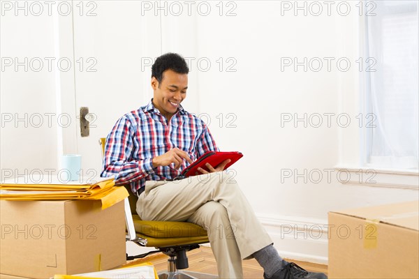 Mixed race man using digital tablet in new home