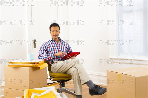 Mixed race man using digital tablet in new home