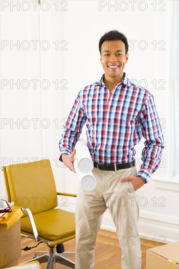 Mixed race man holding blueprints