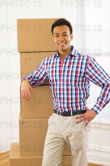 Mixed race man standing by cardboard boxes in new home